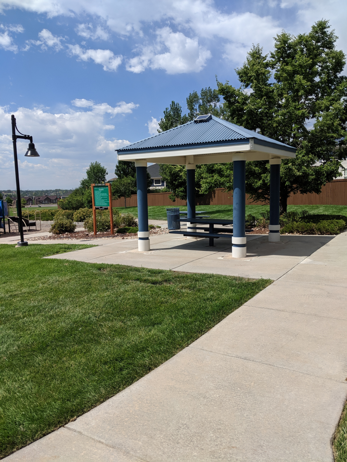 A small pavilion with benches in a sunny park.